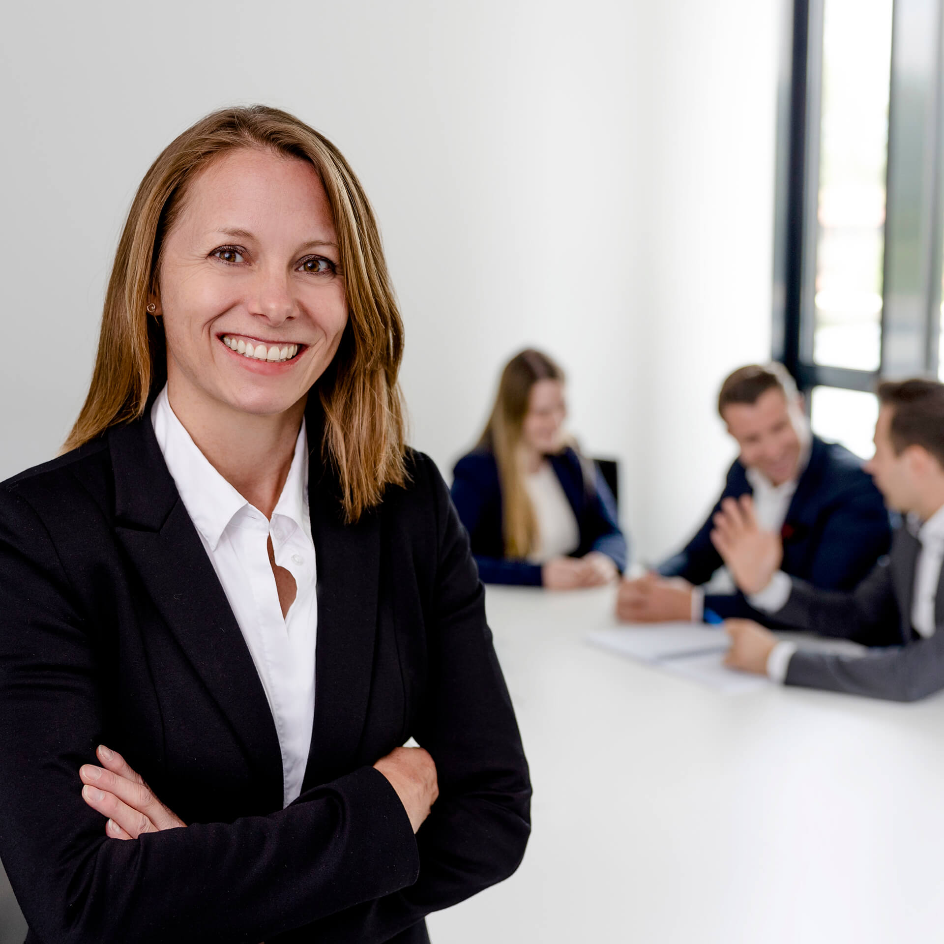 Eine Juristin der Kanzlei activeMind.legal mit ihrem Team an einem Bürotisch.